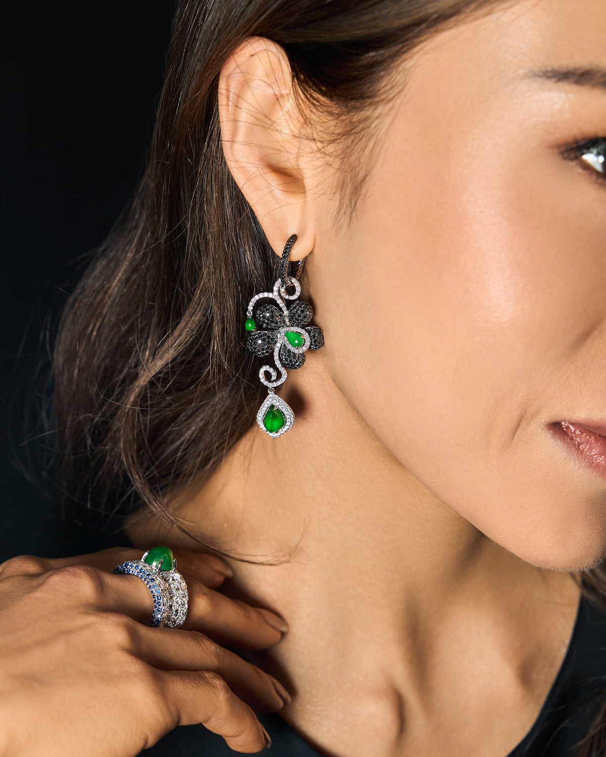 Editorial side profile of model looking to the right, wearing The Black Diamond Floral Earrings prominently visible against the profile silhouette, and The Oval Mosaic Ring on her finger, photographed in natural daylight against a clean backdrop demonstrating the pieces' architectural restraint and suitability for daily wear.
