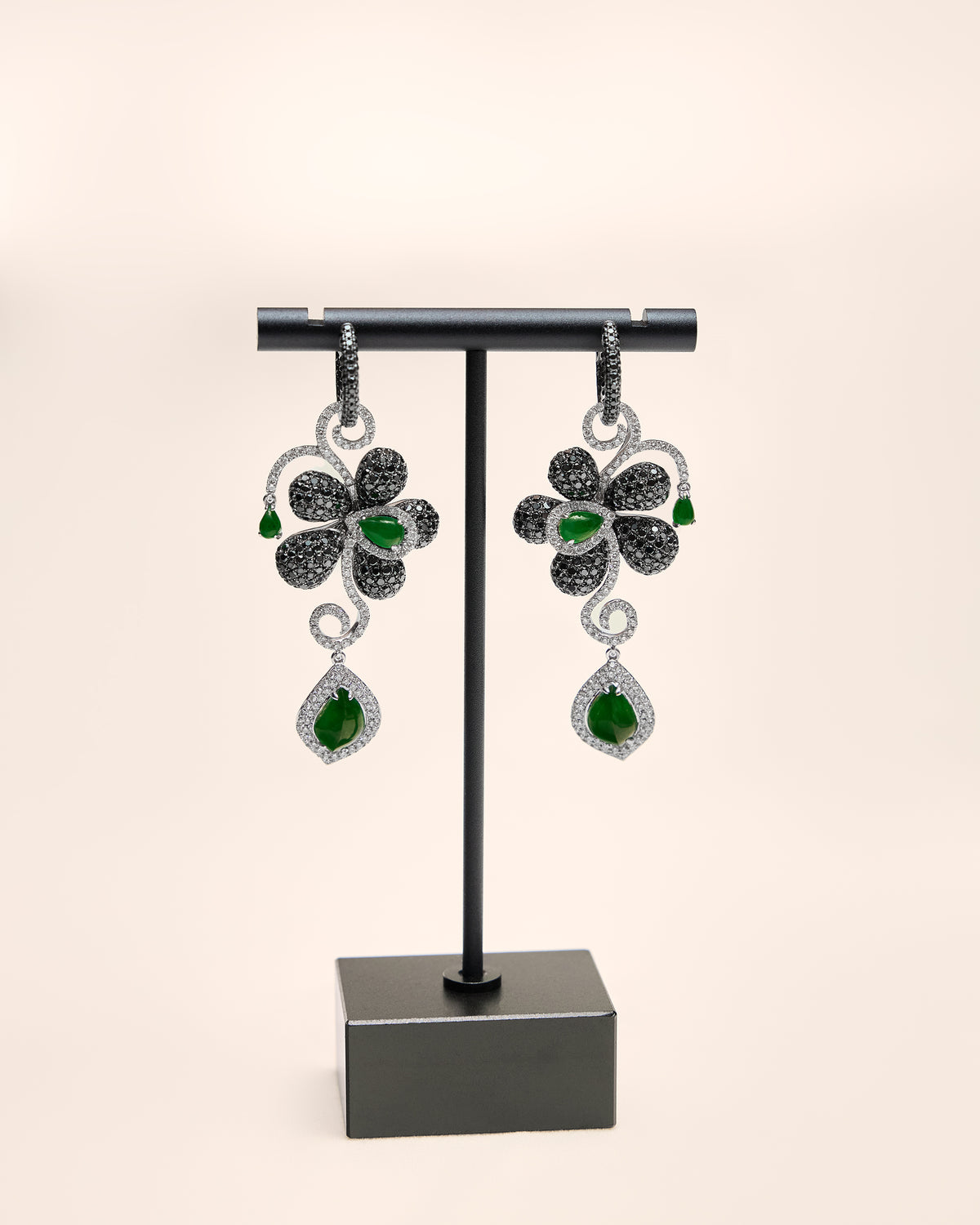 Close front view of The Black Diamond Floral Earrings showing three graduated pear-shaped jadeite cabochons intersecting with pavé diamond scrollwork.