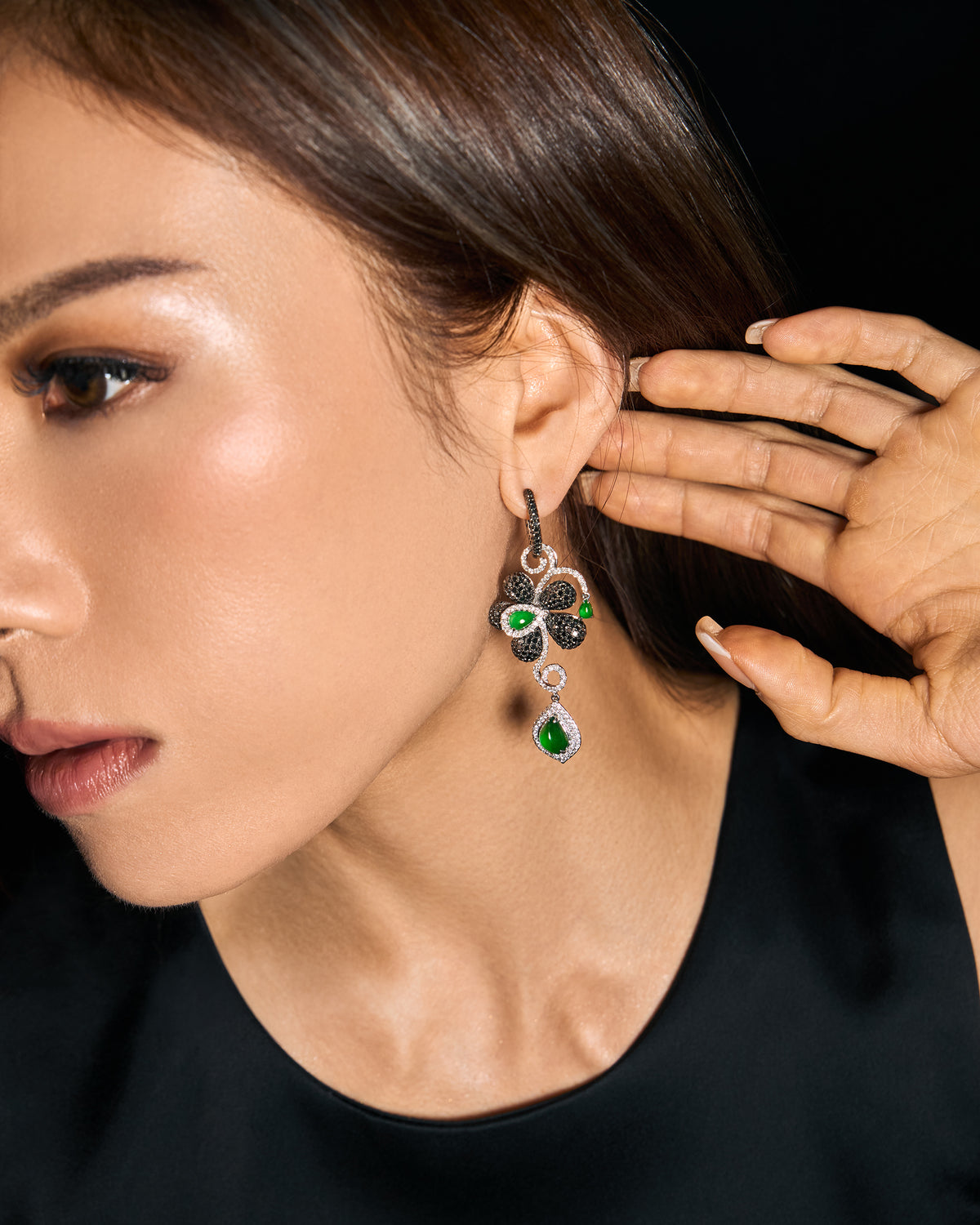 The Black Diamond Floral Earrings worn on a model, the 65 mm drop length and floral silhouette framed by a hand at the ear.
