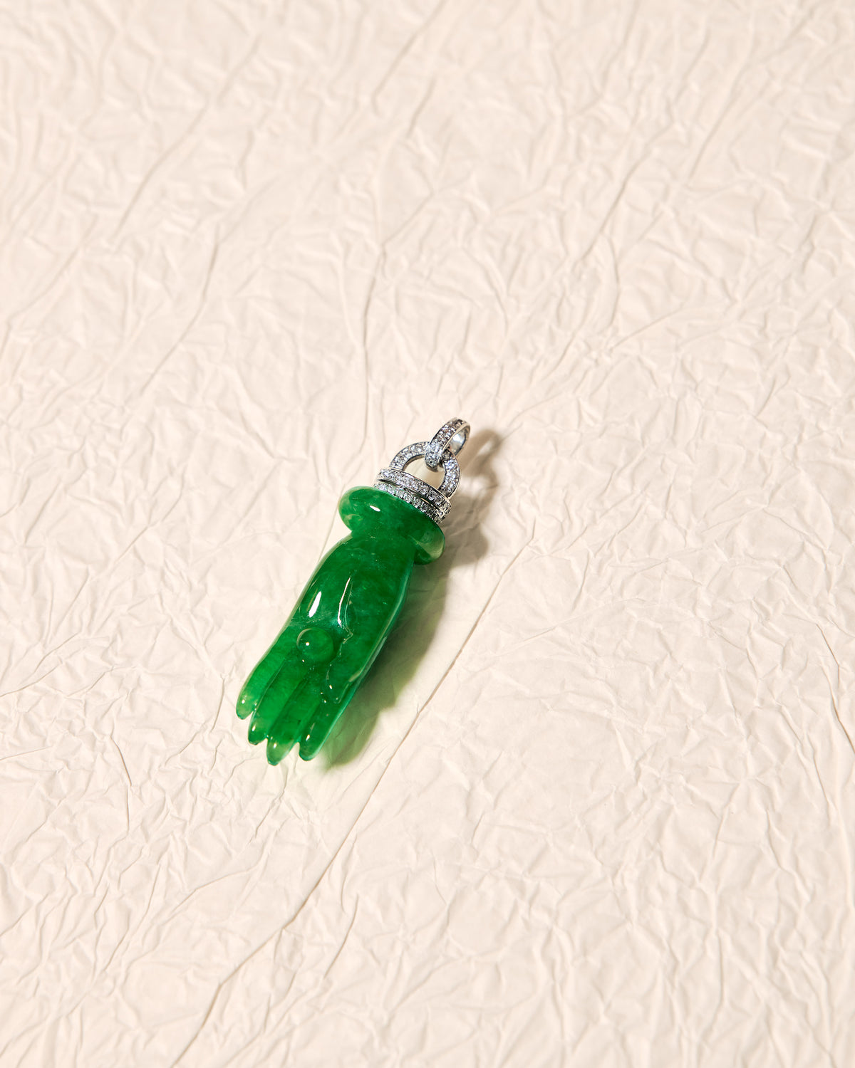 Top-down side view of The Buddha's Palm Pendant on a white background, revealing the sculptural volume of the carved jadeite hand and the articulated structure at the crown.