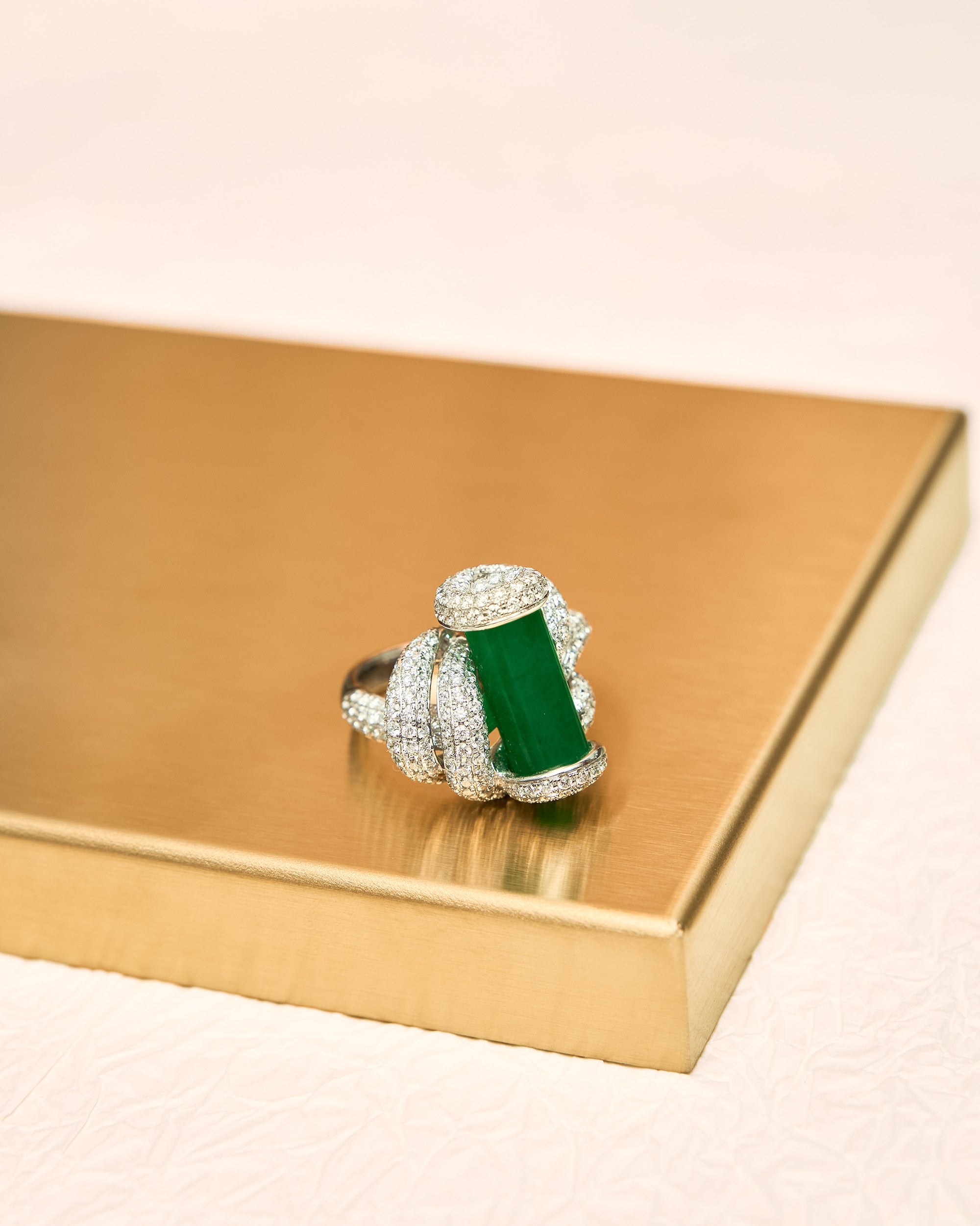 Close front view of The Cylinder Knot Ring showing the upright jadeite cylinder held entirely by the pavé diamond rope knot structure without prongs.