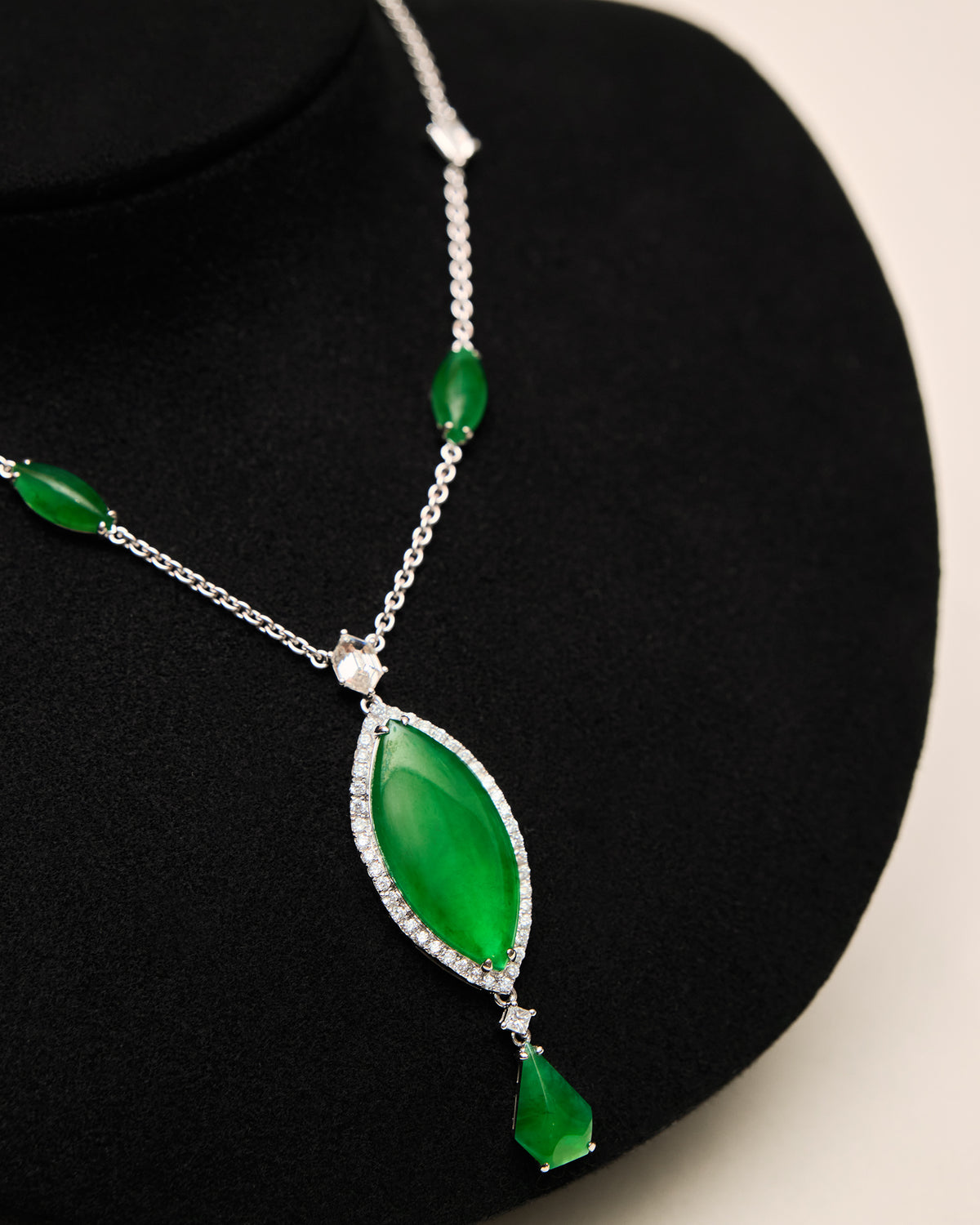 Macro detail of The Marquise Cascade Necklace on a black neck bust, showing the largest marquise-shaped jadeite cabochon framed by round diamond pavé, suspended above an inverted diamond-shaped cabochon, with two smaller marquise-shaped cabochons and the rose-cut hexagon-shaped diamond visible along the chain.