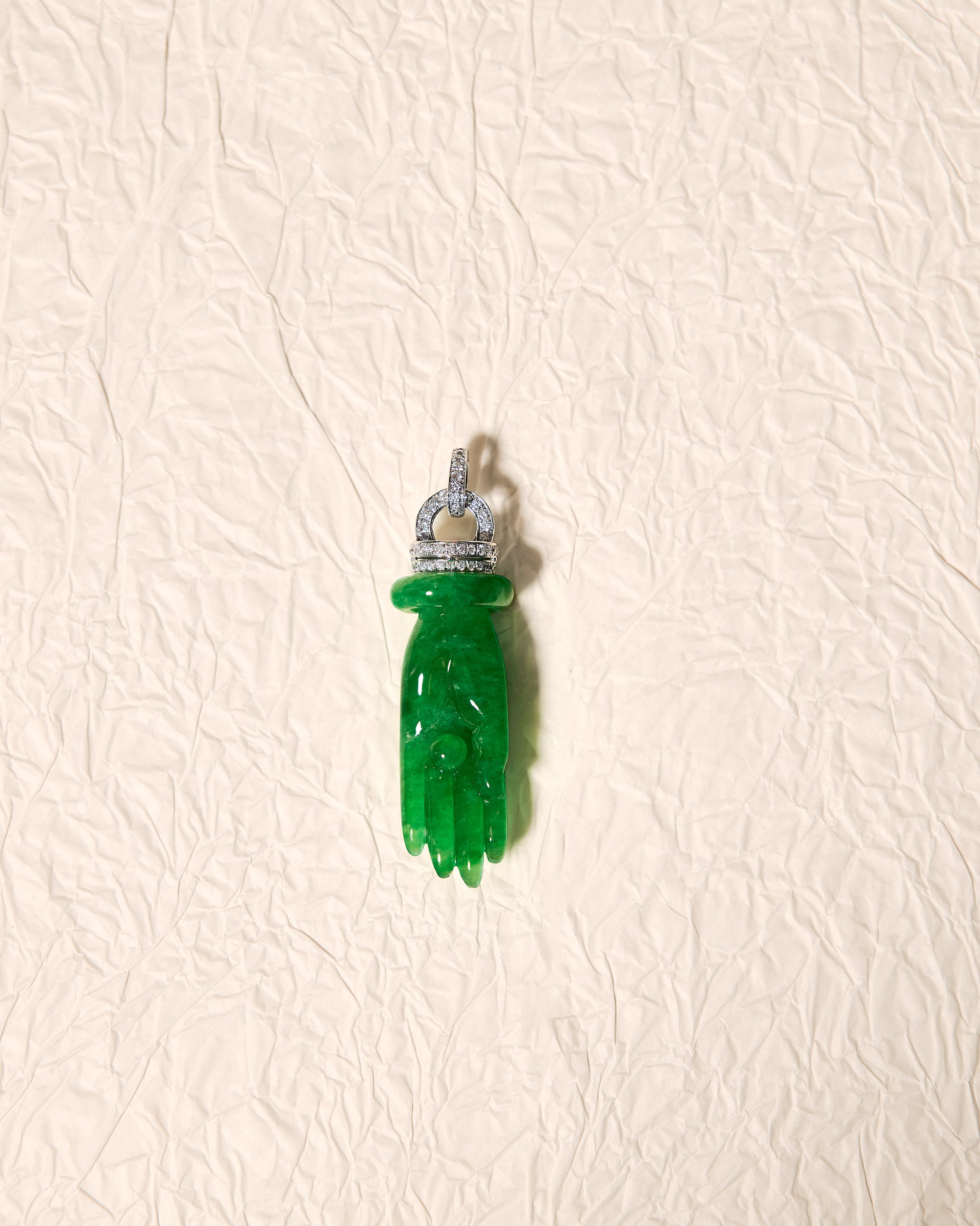 Close front view of The Buddha's Palm Pendant showing the carved palm silhouette, central sphere, and parallel diamond-set rondelles.