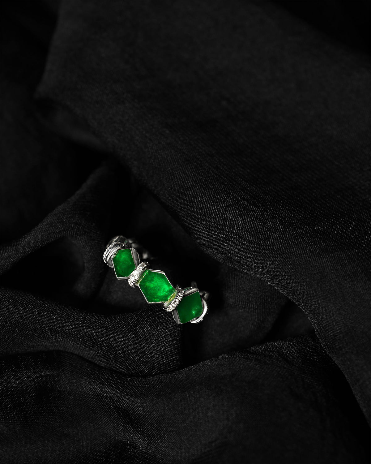 Macro detail of the irregular hexagonal jadeite faces, showing the natural tonal variation and the diamond rondelle separating each stone without prongs.