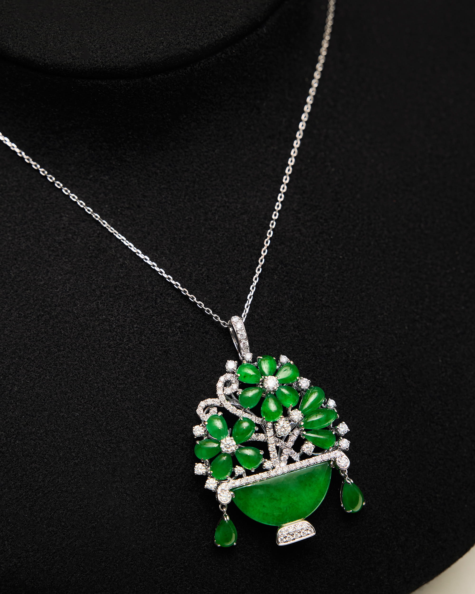 Macro detail of the bright green oval and pear-shaped jadeite petals, round diamond centres, and the concealed metal framework beneath the pavé setting.