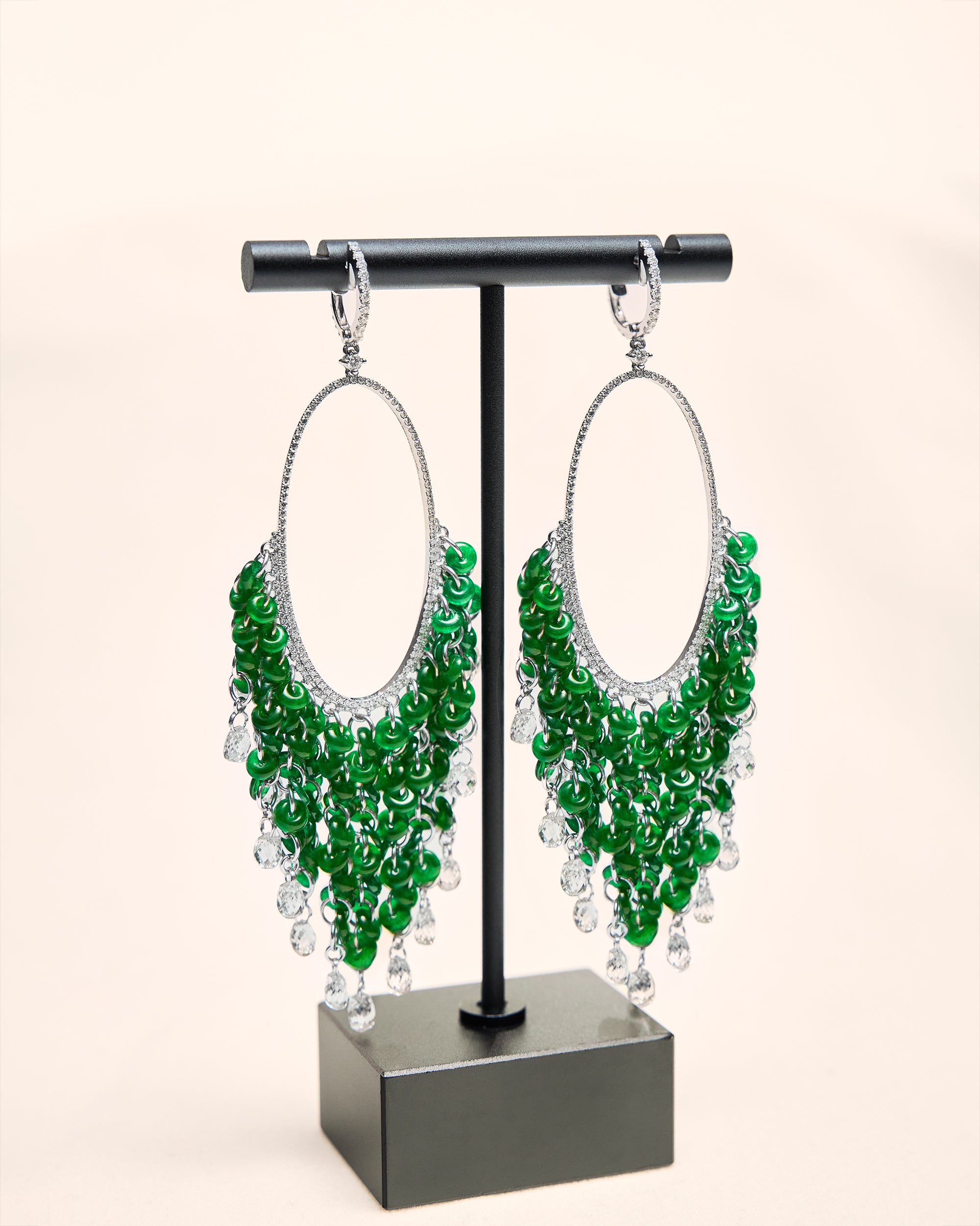 Cascading fringe of intense green jadeite huaigu discs and oval briolette diamonds on a white background, front view showing full drop.