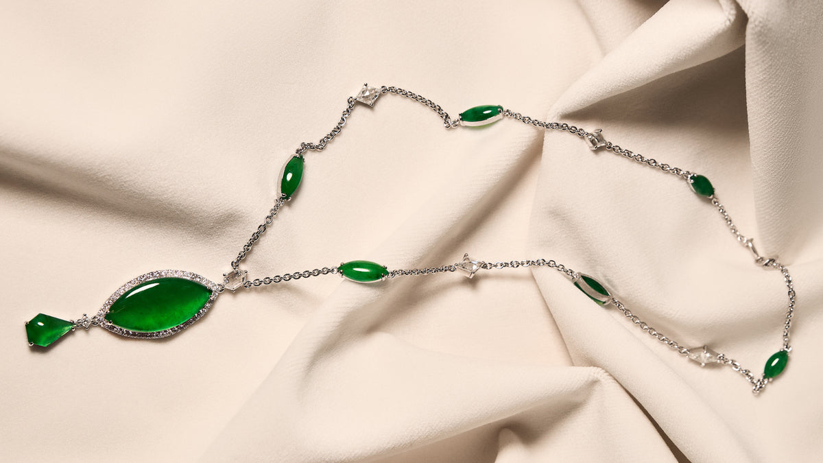 Graduated marquise-shaped jadeite cascade necklace alternating with rose-cut diamonds on an ivory cloth, front view showing the full pendant assembly.