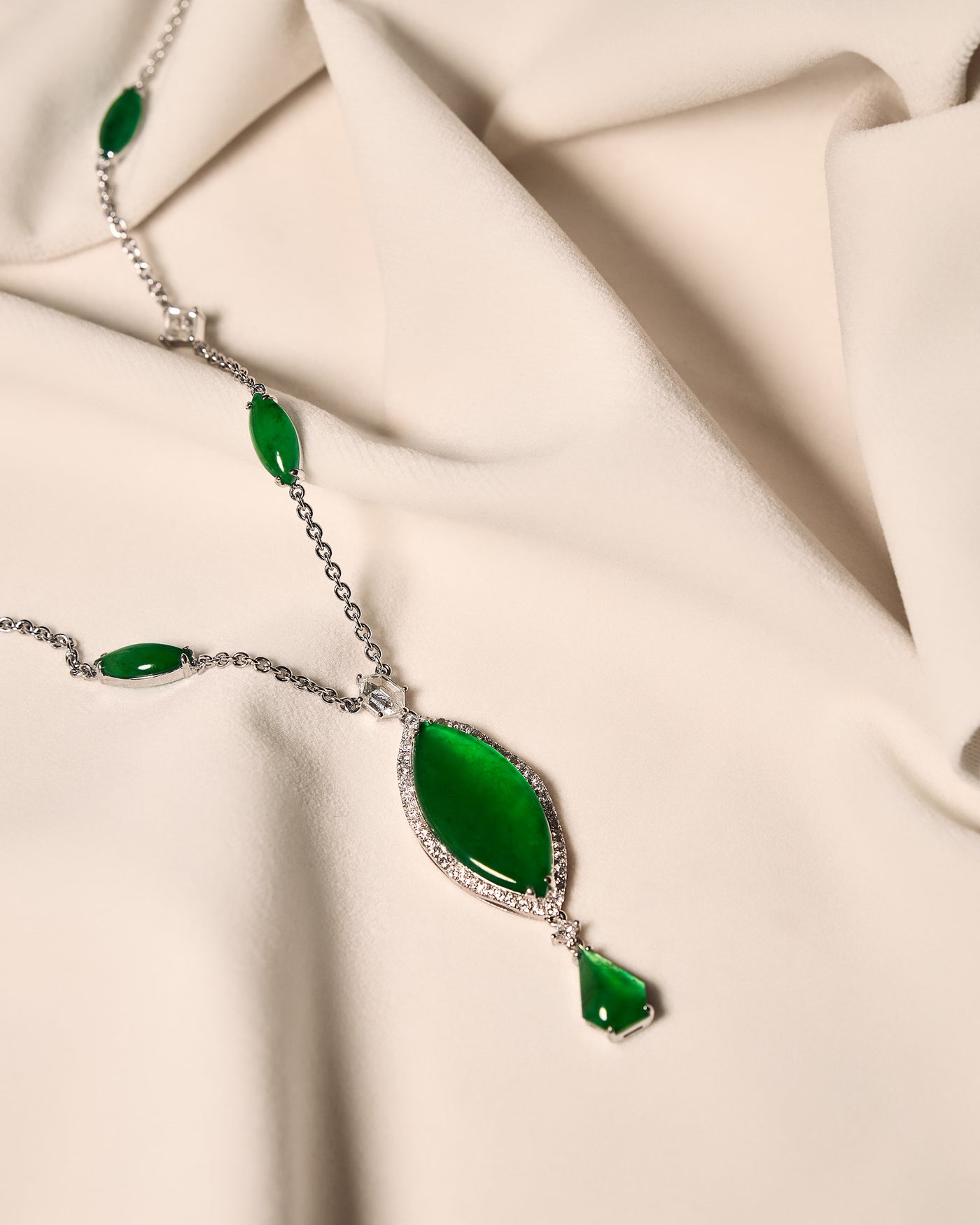Close front view of The Marquise Cascade Necklace on an ivory cloth, showing the precise rhythm of alternating marquise-shaped cabochons and rose-cut diamonds along the chain.