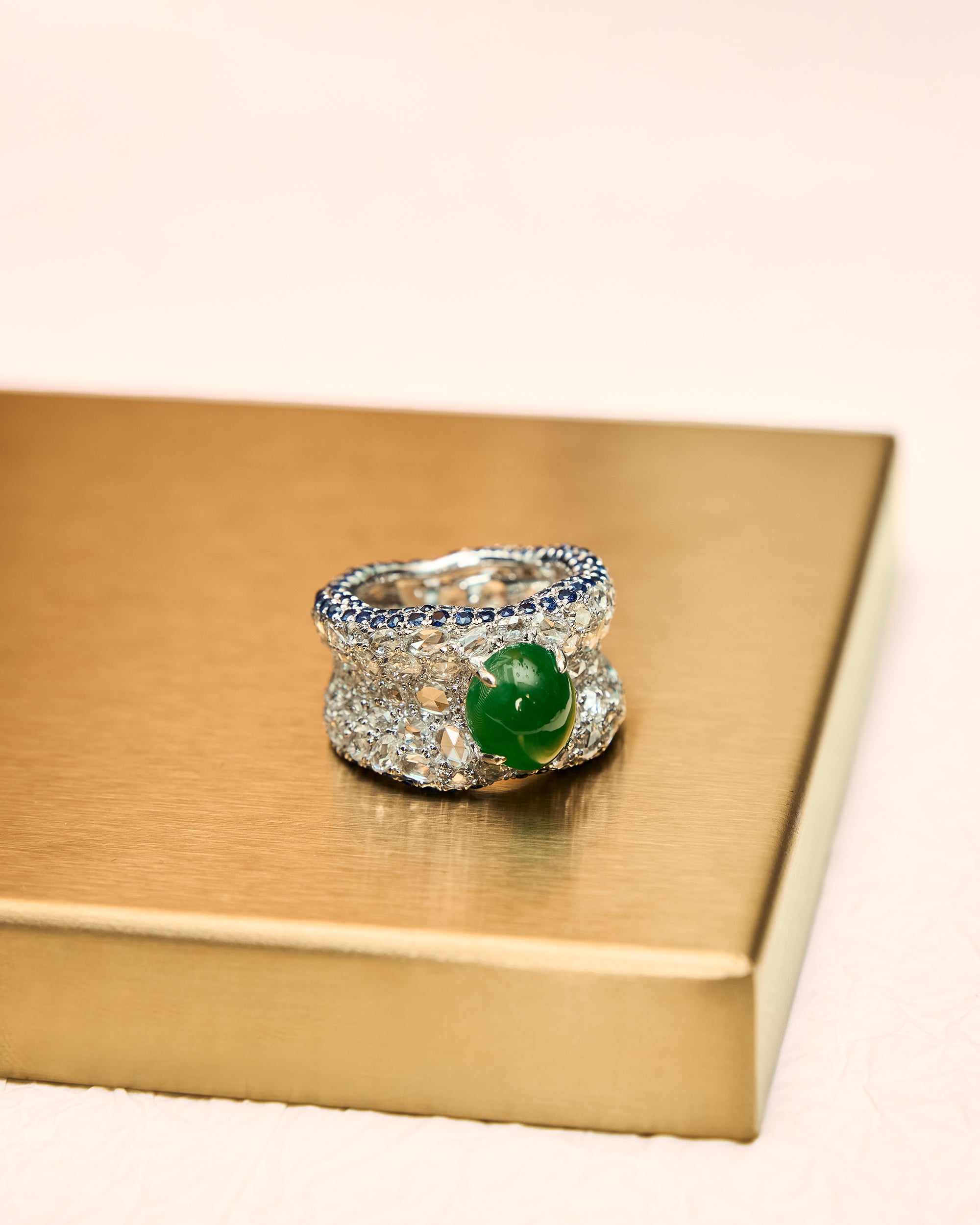 Close front view of The Oval Mosaic Ring showing the full band width, continuous sapphire border rows, and the central oval jadeite dome.