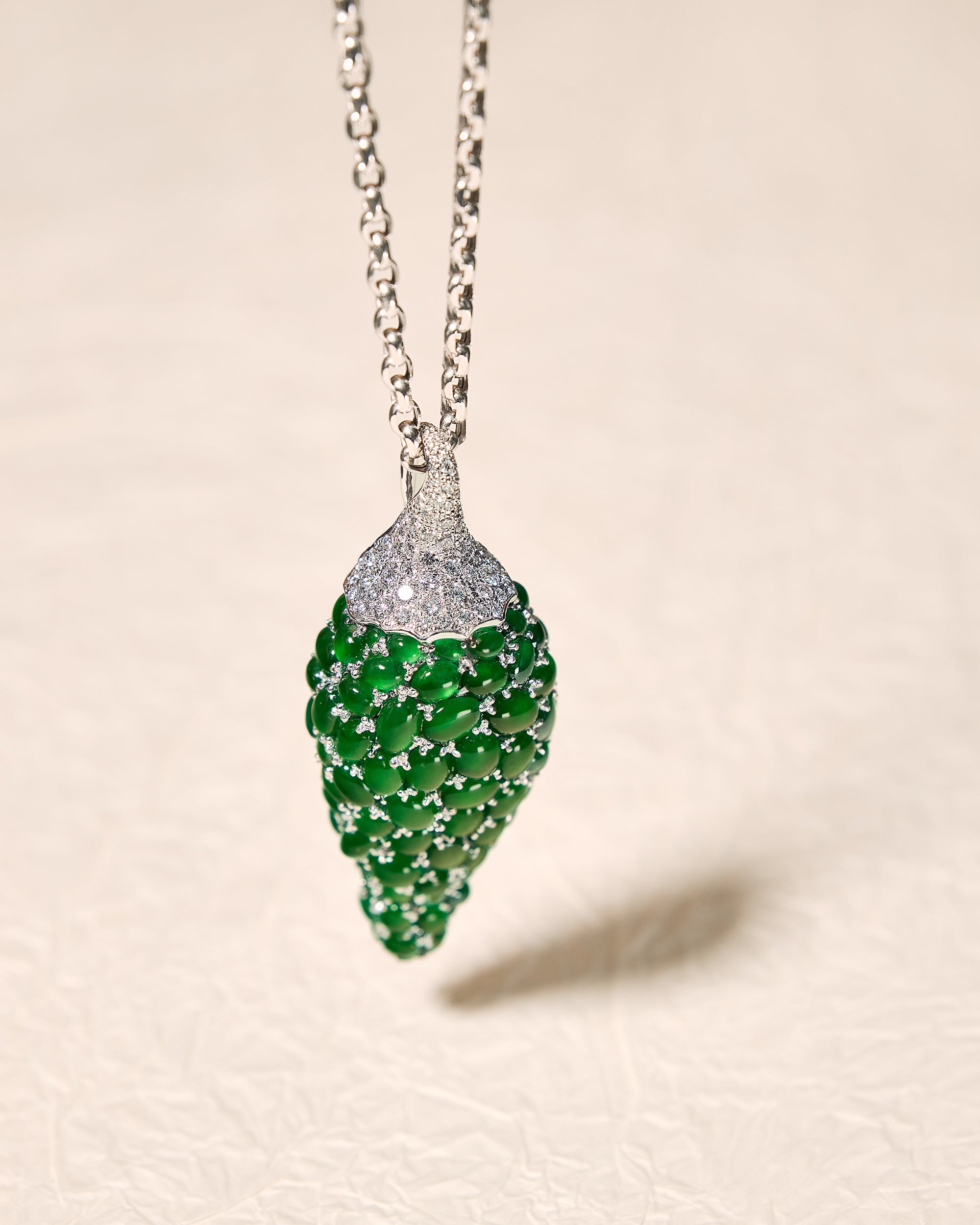 Macro detail of the finely translucent emerald green oval cabochons nestled within the pavé-set diamond background, showcasing the vivid lifelike presence.