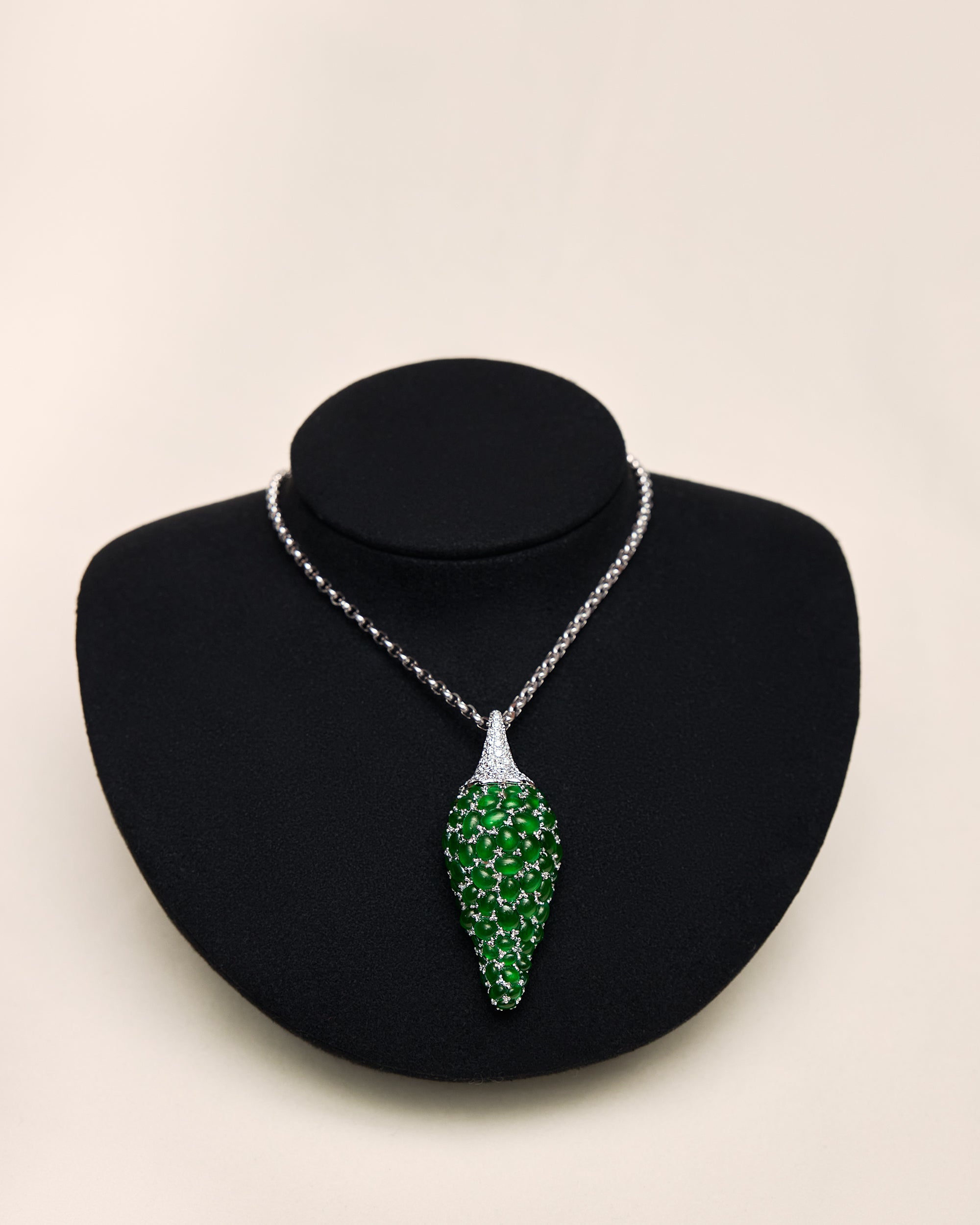 Close front view of The Pepper Motif Pendant on a black neck bust, showing the sculptural volume of the graduating jadeite stones and the continuous pavé diamond stem.