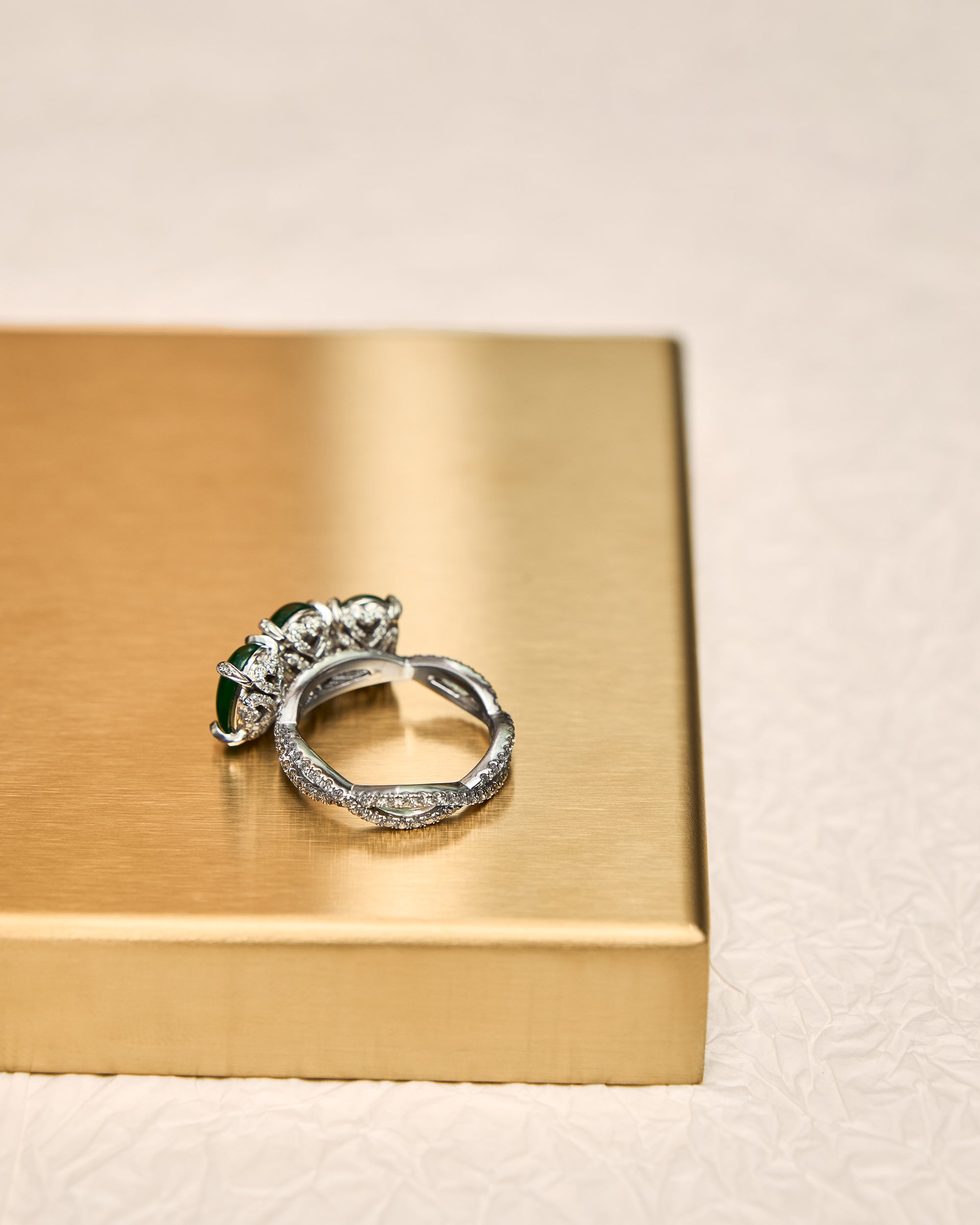 Rear view of The Trilogy Oval Cabochon Ring showing the reverse side of the setting, the elevated pavé baskets, the minimal prongs securing the three oval jadeite cabochons, and the intertwining pavé diamond band.